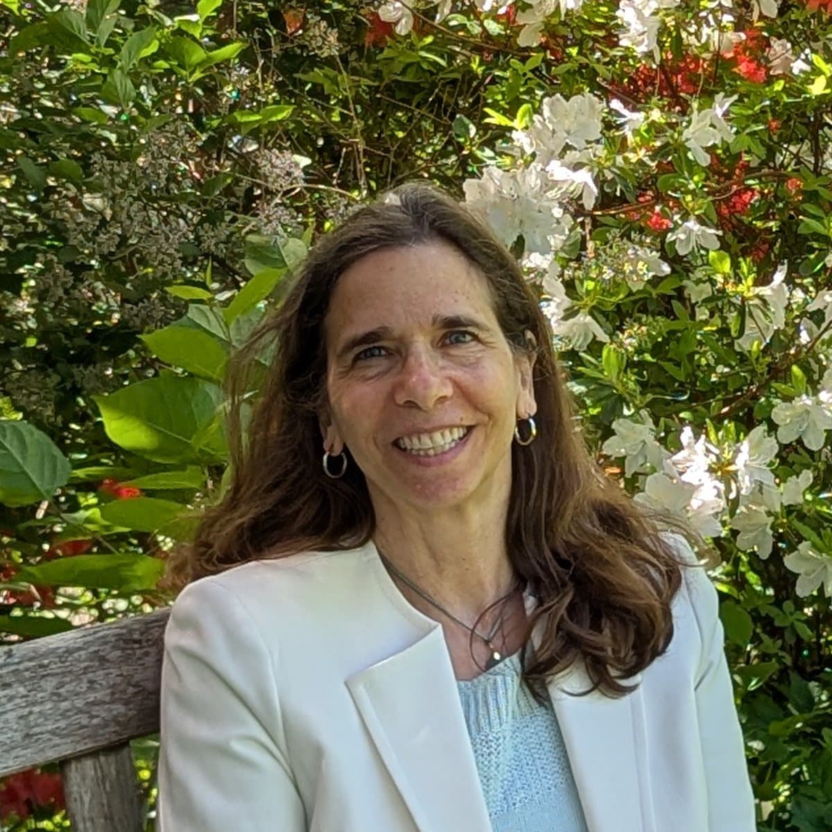 Rebecca Gotterer smiling on a garden bench in front of flowering azaleas